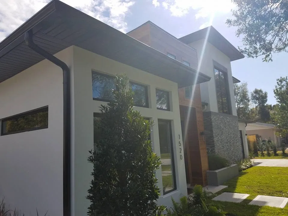 Modern white stucco entry dark fascia gutter downspout wood accent stacked stone